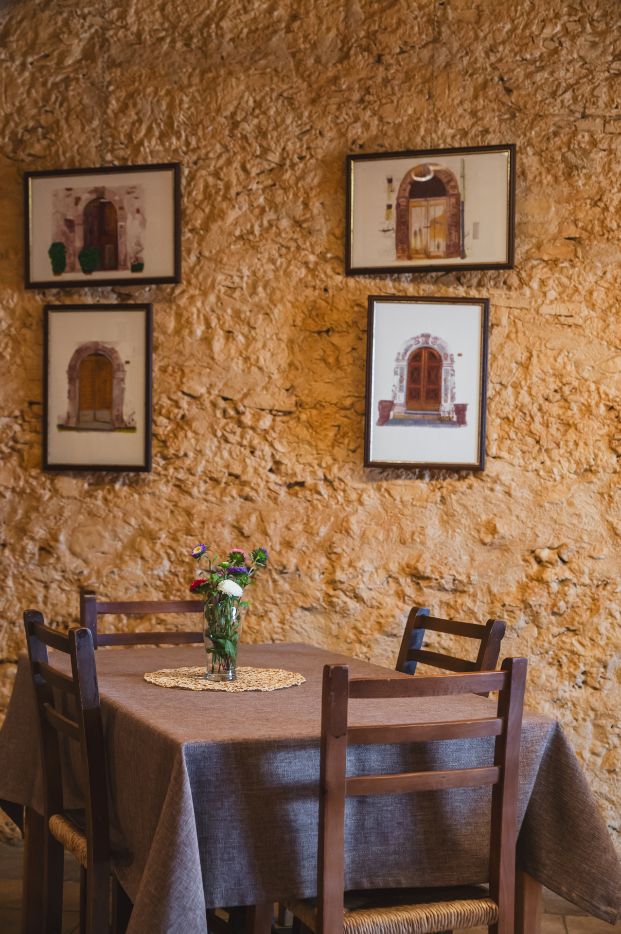 Sala interna del ristorante Le Baccanti a San Marco Argentano con tavolo e quadri su muro in pietra